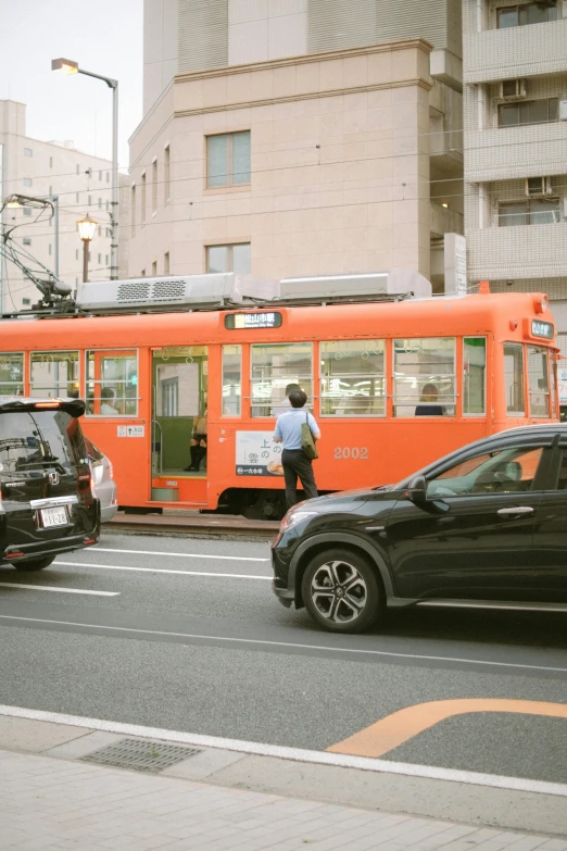 a red bus traveling down a street past cars