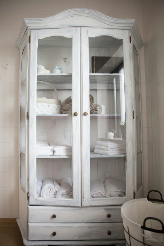 white wooden armoire filled with towels and baskets