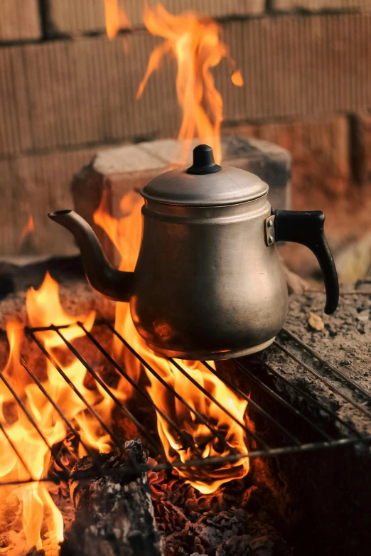 a kettle sits on a grill on top of the flames