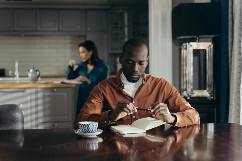 man eating at the table with his wife preparing food behind him