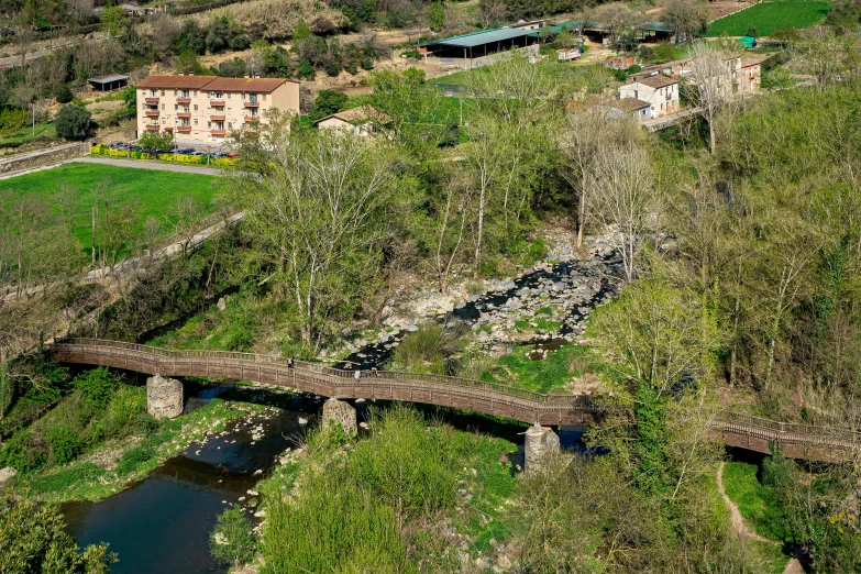 an aerial view of a river, bridge and small homes