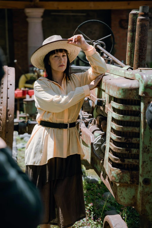 woman in brown outfit leaning on old tractor