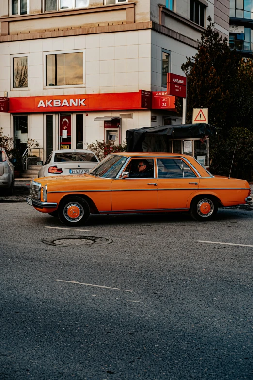 an orange car parked in the street by a store