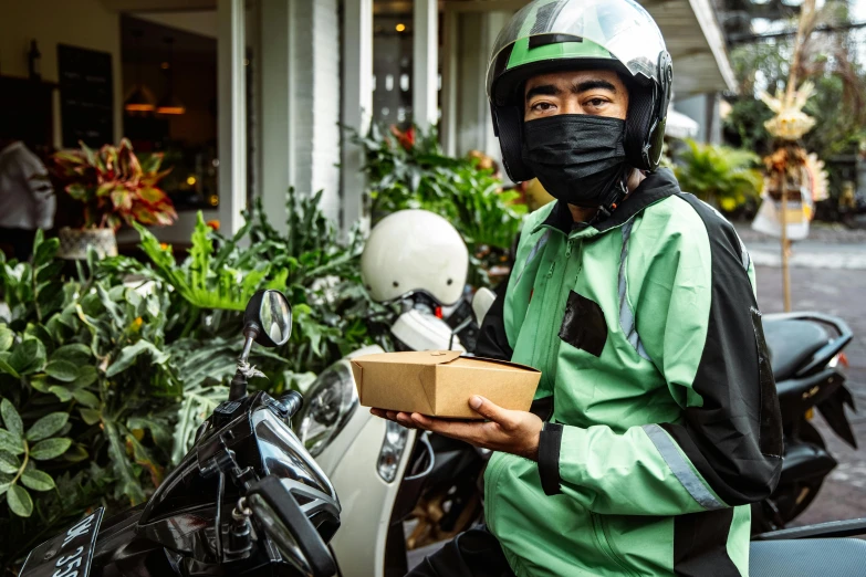 a man is on a motorcycle holding a package