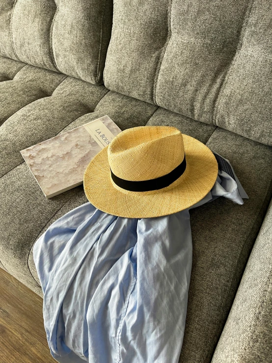 hat and clothes laying on couch with cloth and pillow