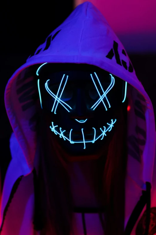 person in a hoodie with glowing face mask in the dark