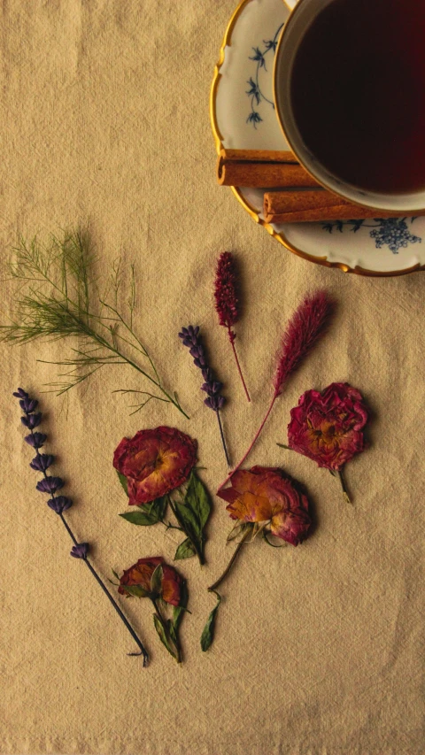 a plate and cup filled with flowers next to some cinnamon sticks