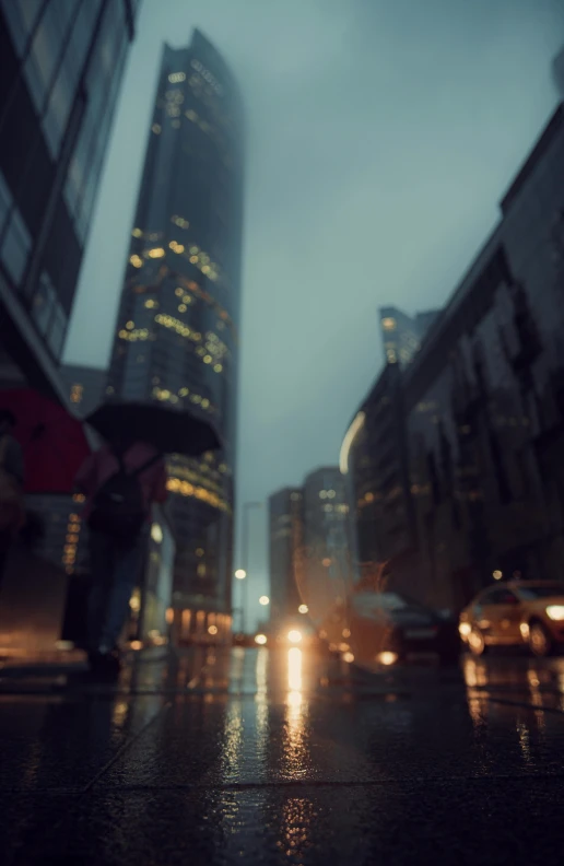 people with umbrellas cross the street at night