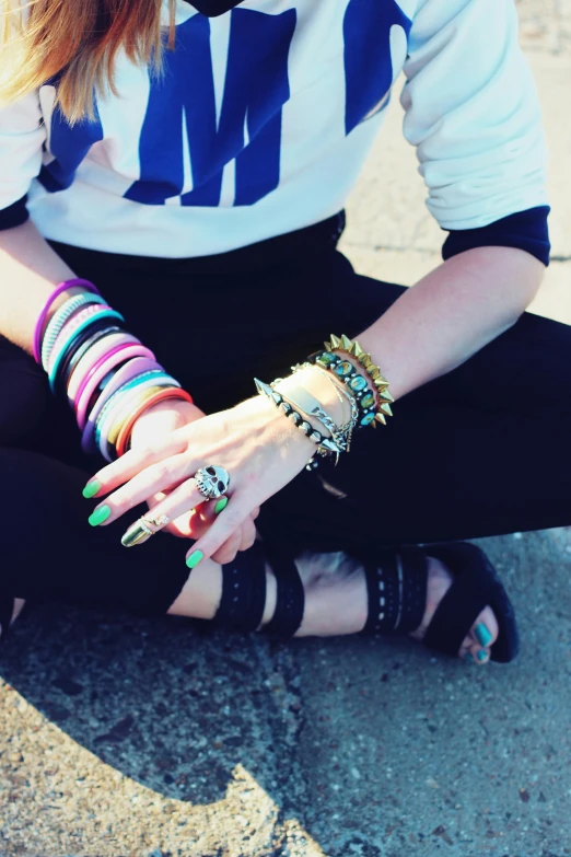 a person sitting on the floor wearing multi colored jewelry