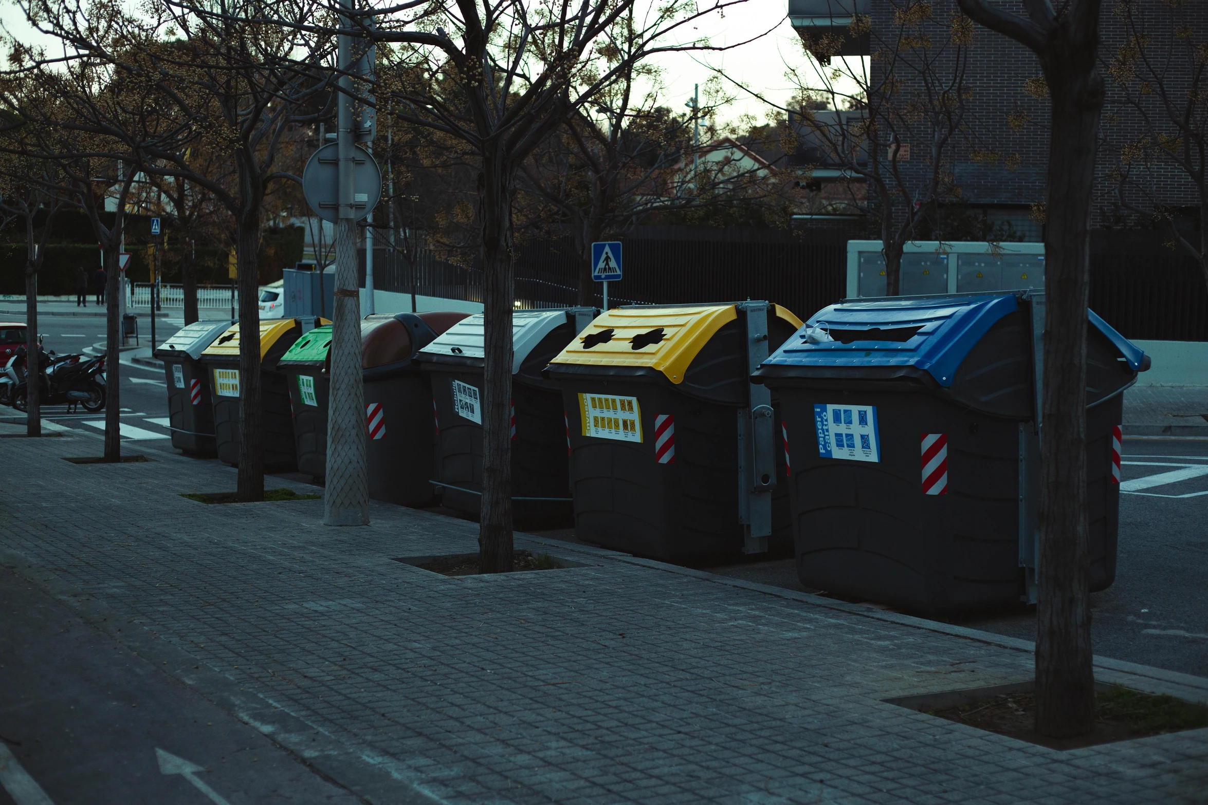 a row of trash cans on the side of a road