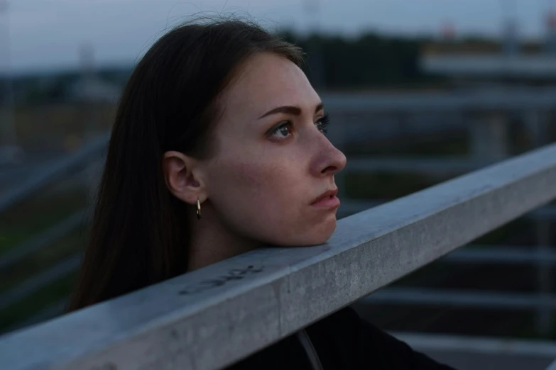 a woman looking at soing behind her while on the edge of a bridge