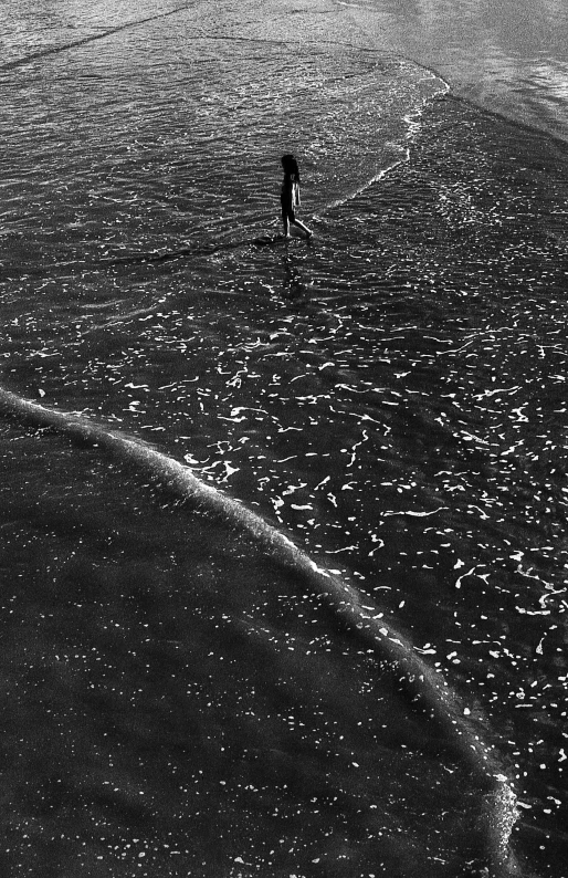 a man walking through the ocean on his surfboard