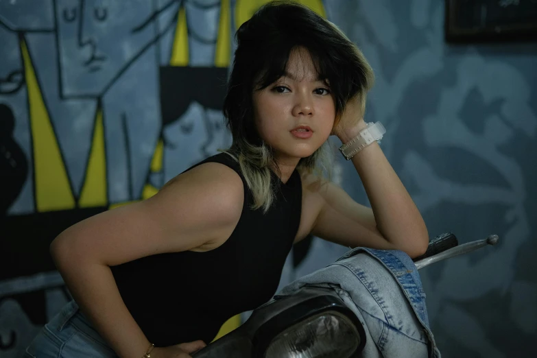 a pretty young woman sitting in front of a wall