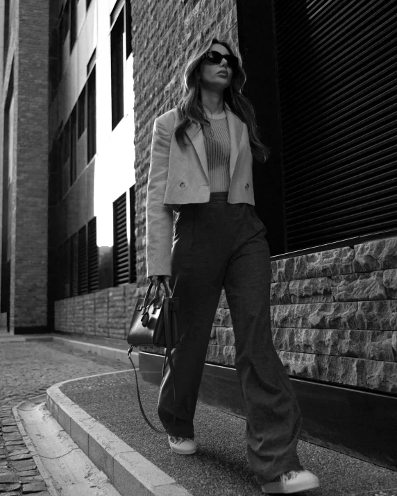 a woman in an all - white sweater and jacket is walking down the street