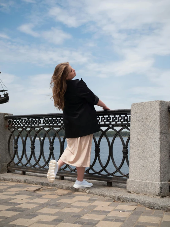 a woman looking down while standing on a bridge