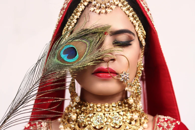 the woman is dressed in all red and has an ornate peacock - feather decoration on her head