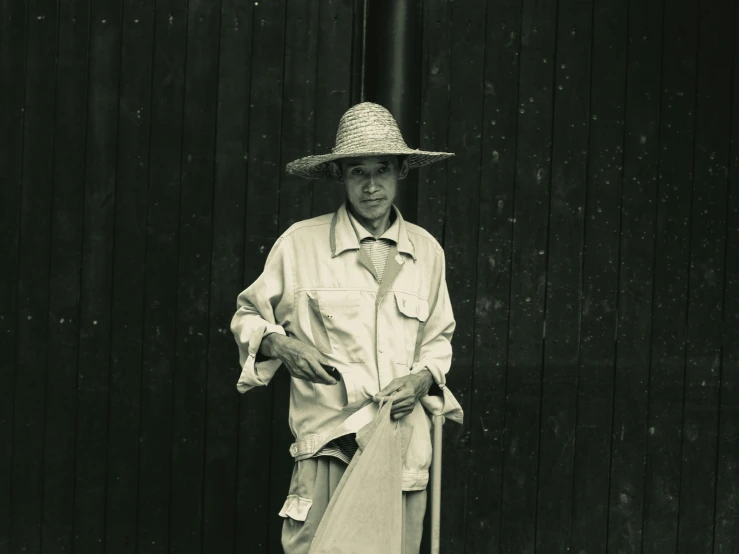 a man standing in front of a wooden wall with a stick