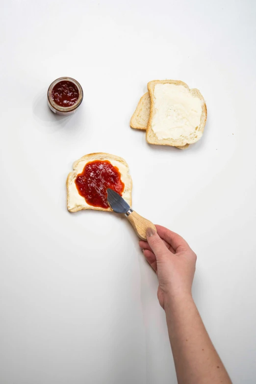 a person putting jam on toast bread with a er knife