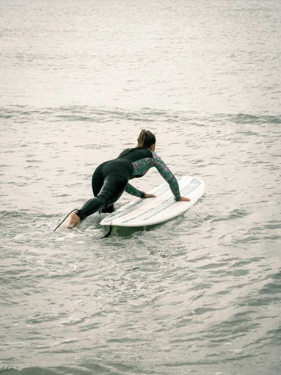 man riding white surf board with wet suit on