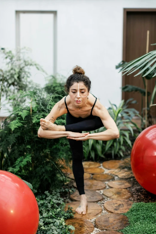 a woman does a yoga pose among two large balloons