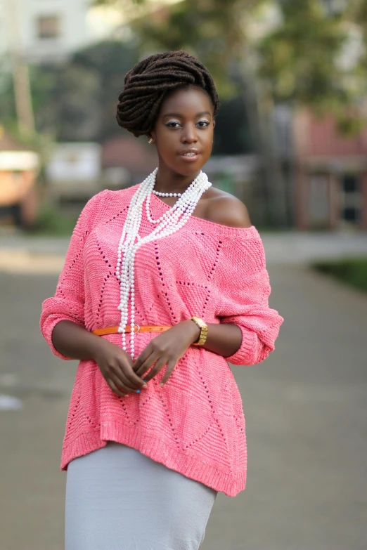 woman in a pink sweater and pearls is walking