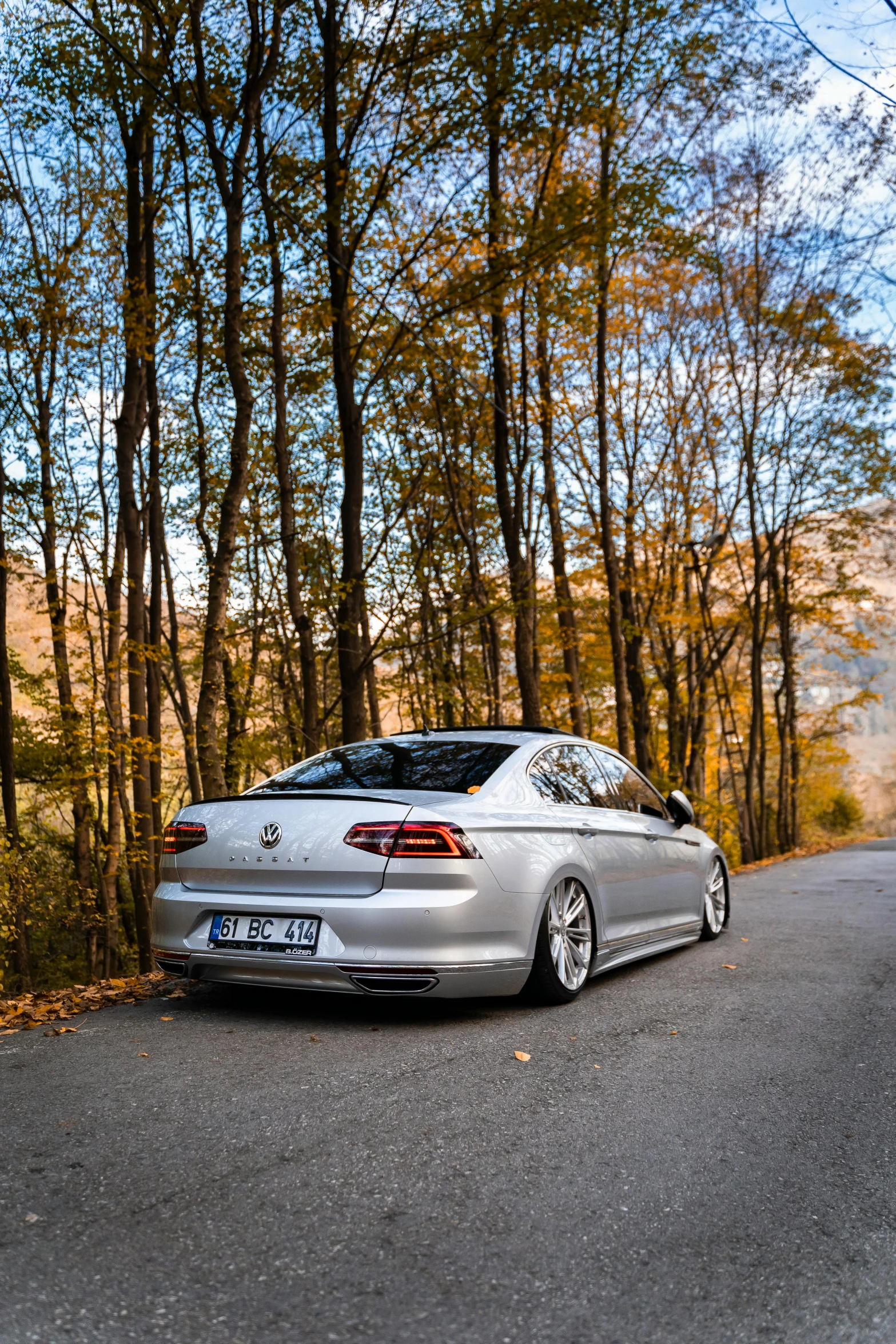 the car is parked on the side of the road in front of the trees