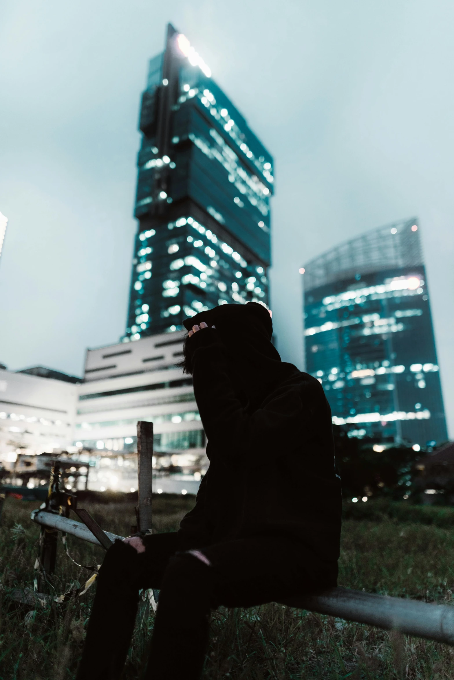 the man is sitting on the bench looking at the building