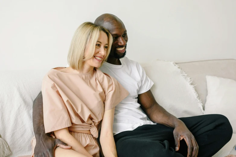 a man and woman are sitting on a white couch