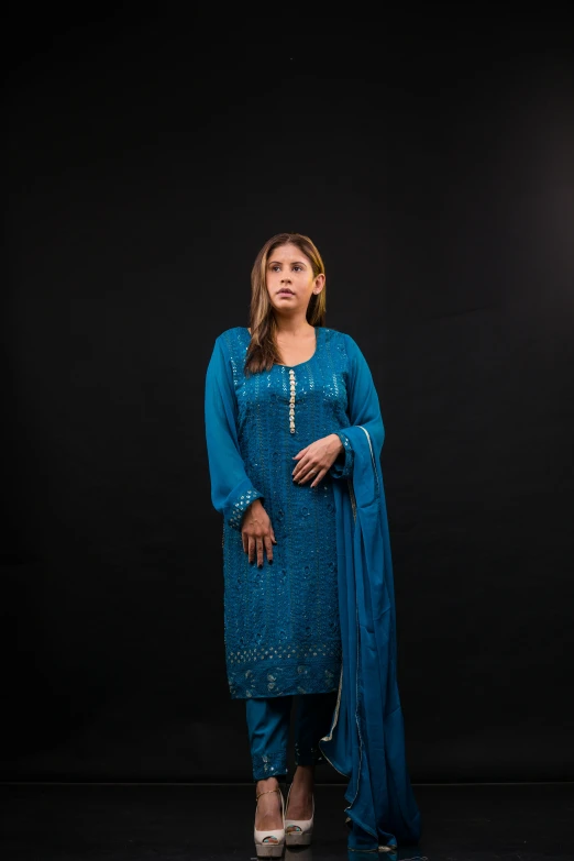 woman in turquoise outfit posing on black backdrop