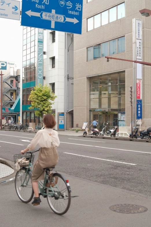 woman on bike going under street sign in urban area