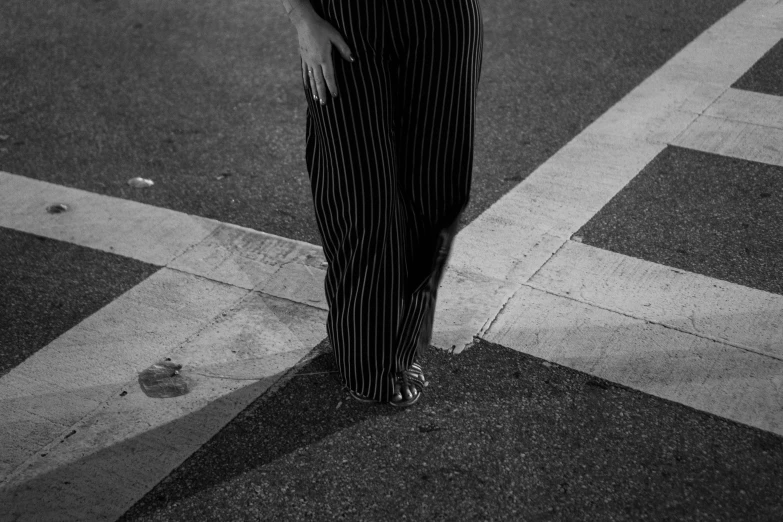 a woman wearing a tie and striped pants standing on a sidewalk