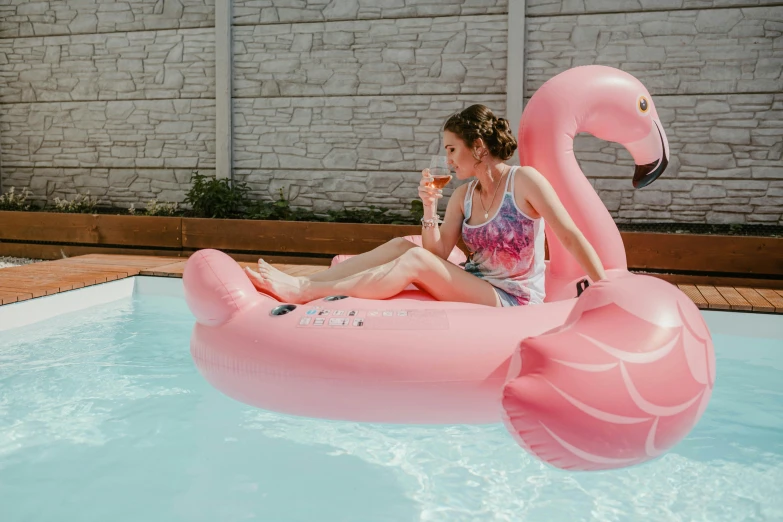 girl in pink bathing suit sitting on an inflatable flamingo