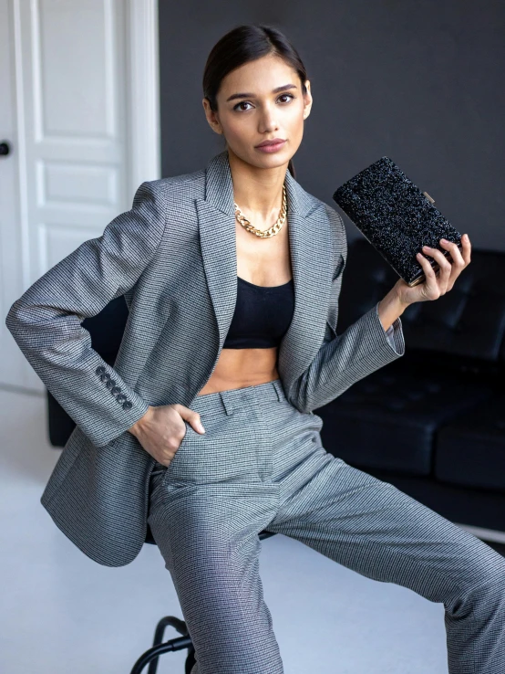 a woman posing in her suit with a clutch