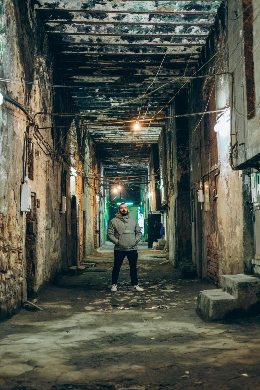 man in grey jacket walking down a run down alley