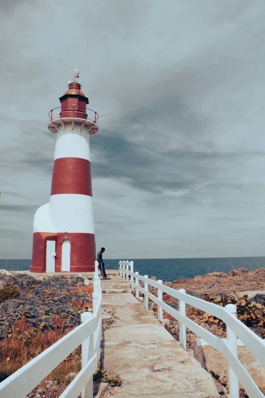 a wooden path with a lighthouse next to the ocean