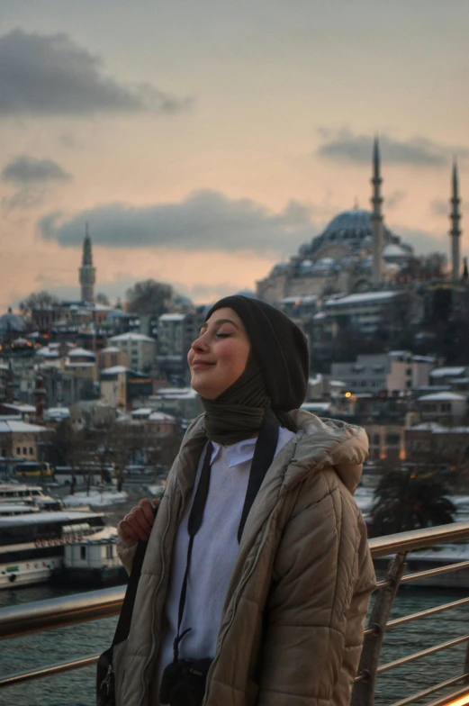 a woman standing in front of a city skyline at sunset