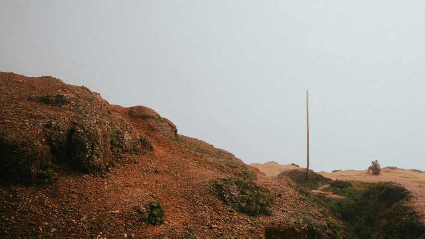 a lone horse sitting on top of a dirt covered hillside