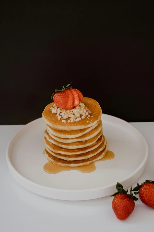 some pancakes with strawberries on top on a white plate