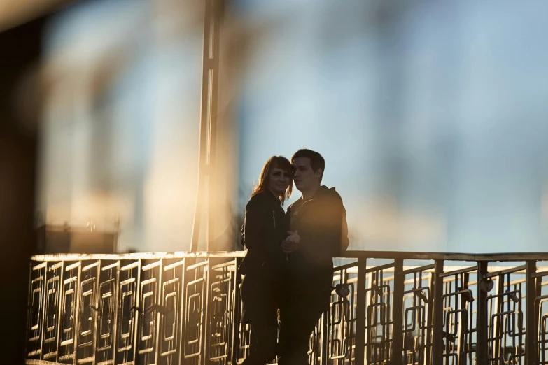 two people standing on the side of a bridge near one another