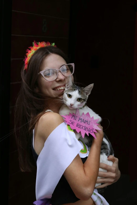 a woman holding a kitten while wearing glasses