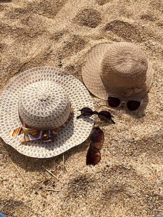 hat and sunglasses laying on sand at the beach