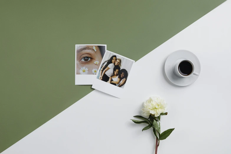 a coffee cup sits next to two pos on a white table with a flower on top