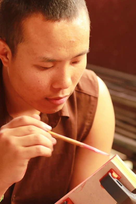 a man holds up a pencil to paint a piece of art