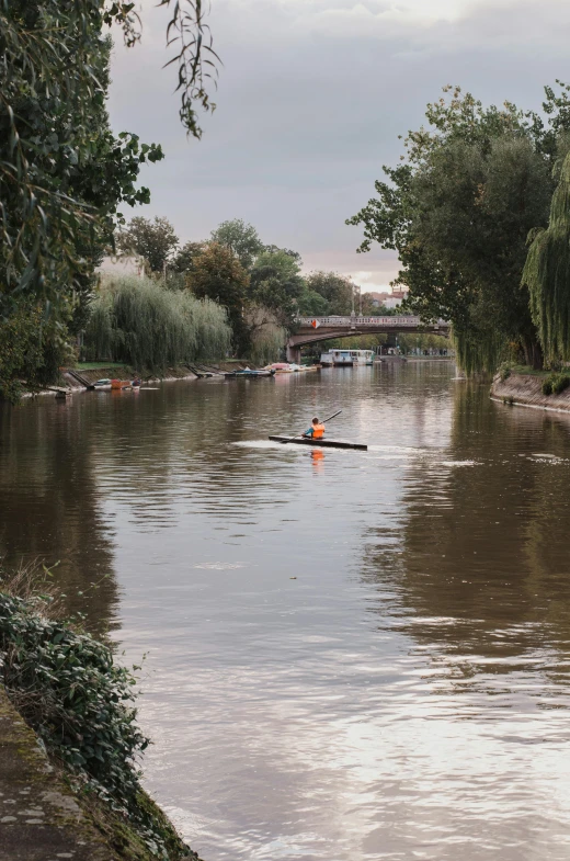 man paddling canoe in very deep water, looking over bridge