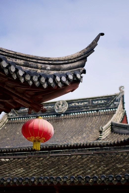 a chinese roof has a large red lantern attached to it