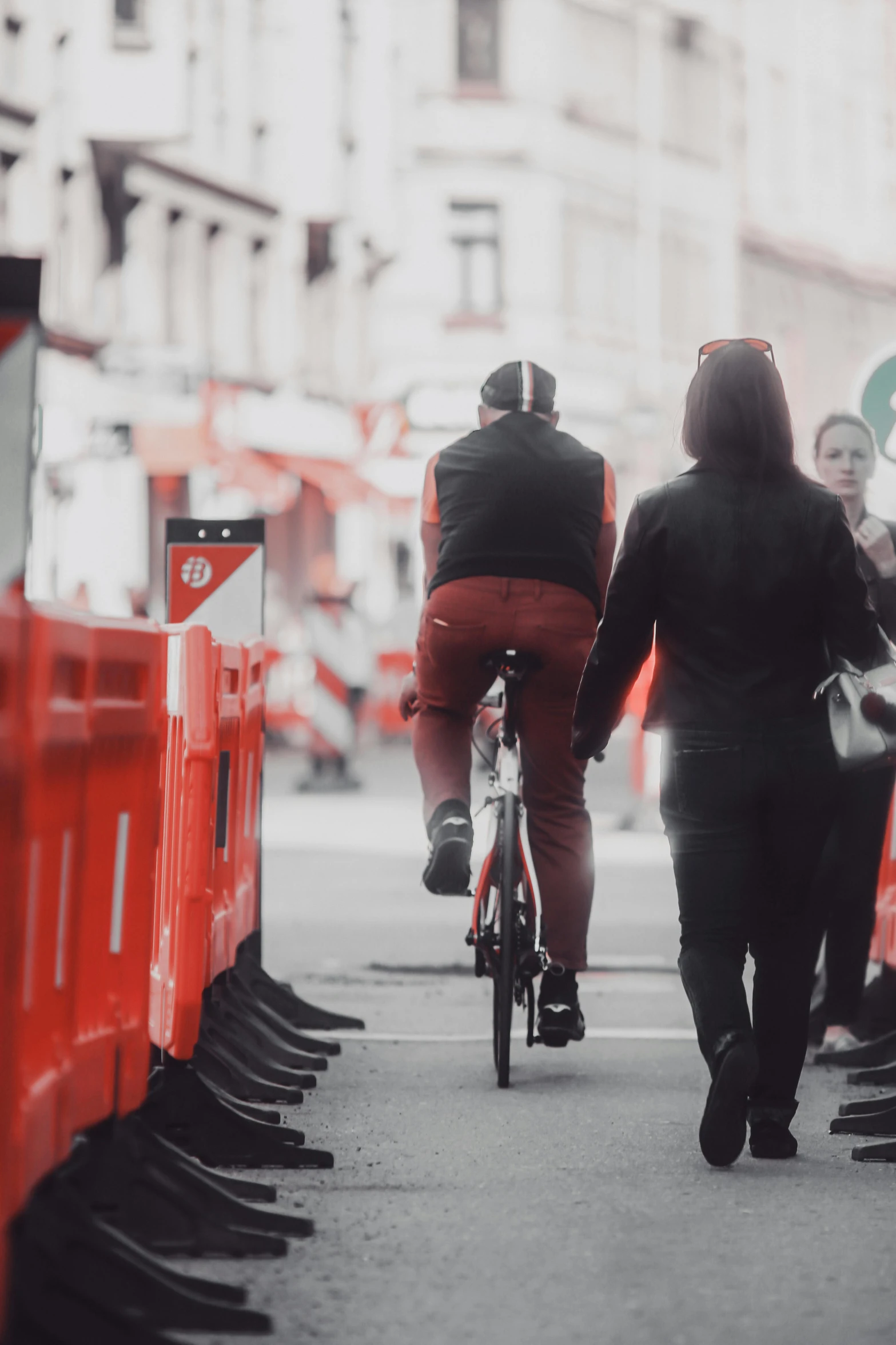 several people are biking on a street next to construction gates