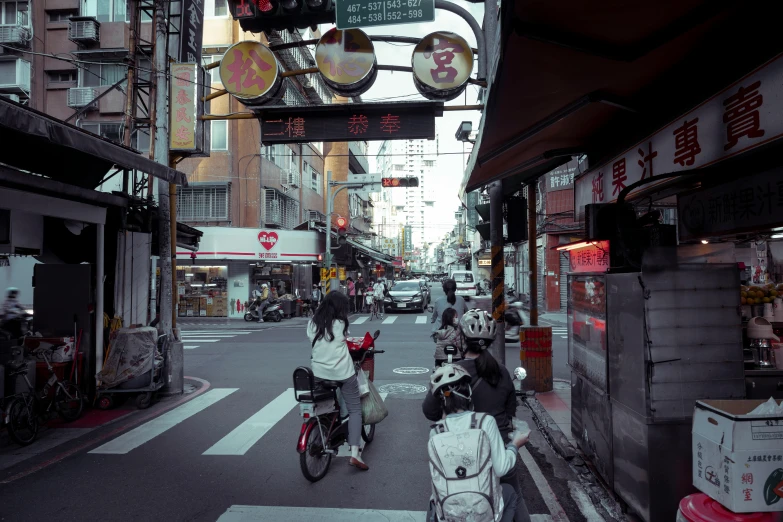 several bicyclists driving past the sidewalks in an asian market area