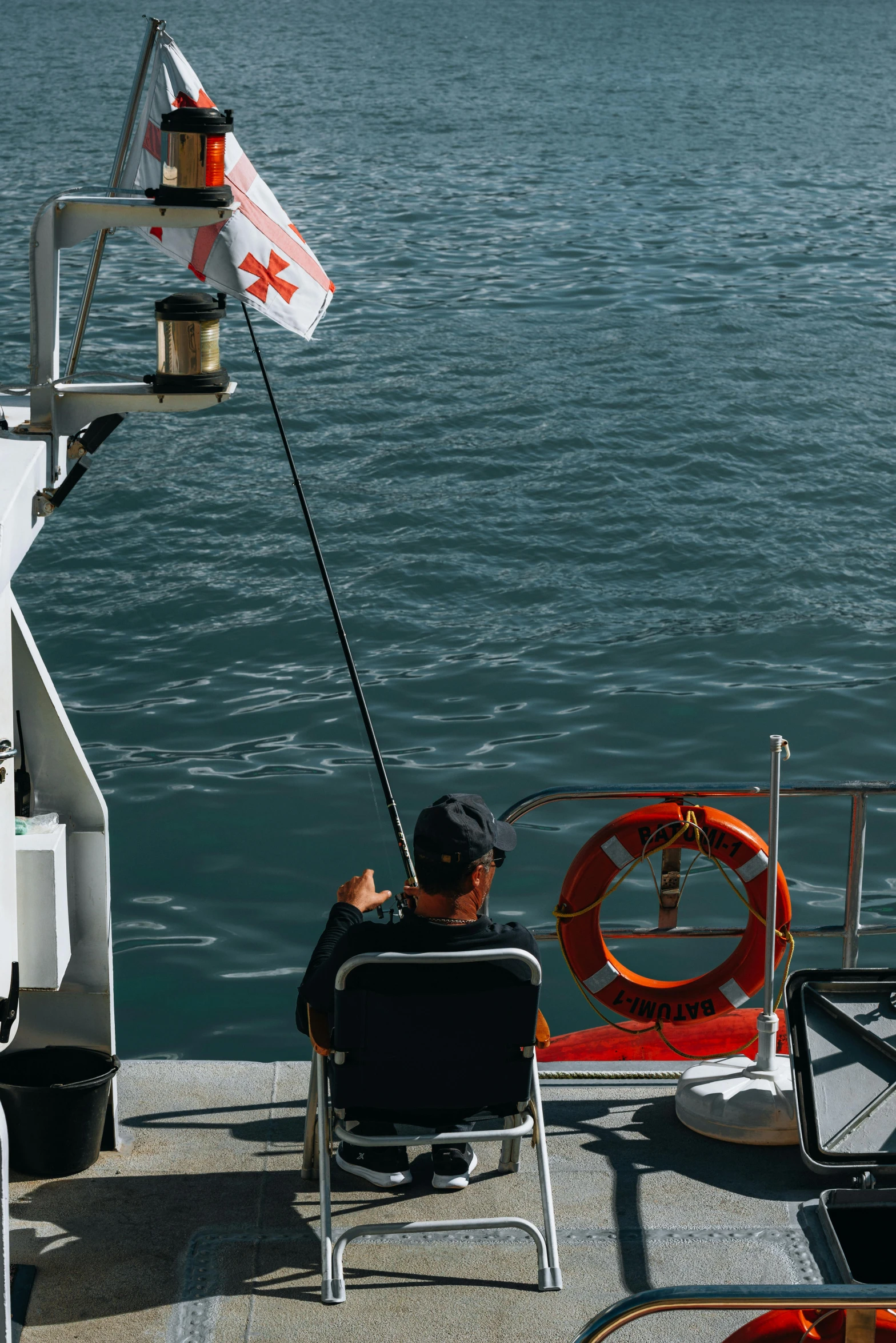 a man sitting in a chair fishing off a boat deck