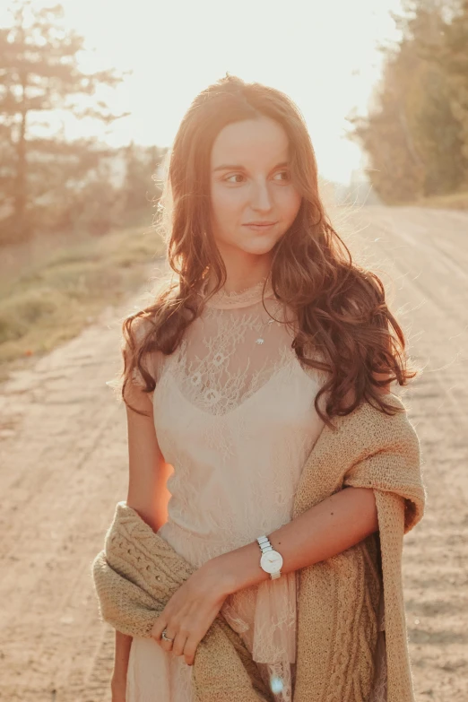 a woman wearing a dress and a lace top on a dirt road