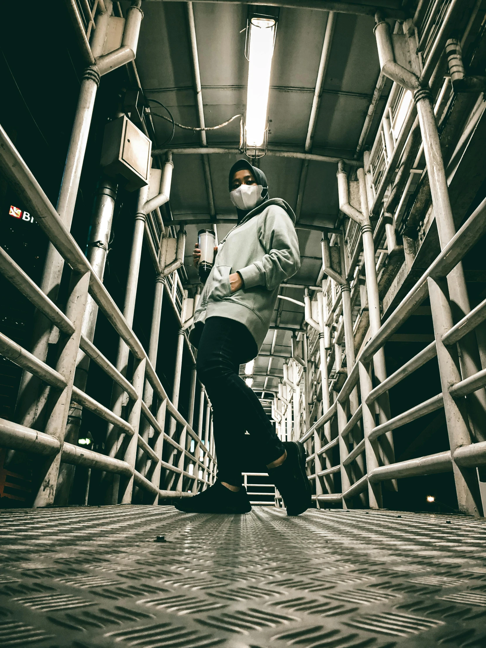 a person walks down a tiled walkway wearing a mask